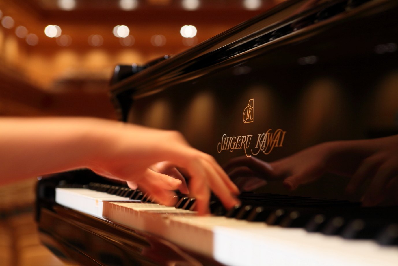 Les mains d'une pianiste sur le clavier d'un piano de concert Shigeru Kawai